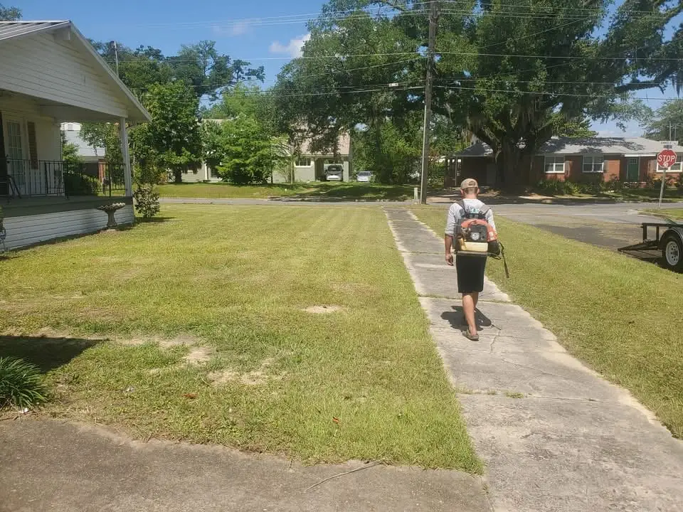 A Faith Lawn Care crew member clearing grass clippings off the walk with a backpack blower after a fresh mow