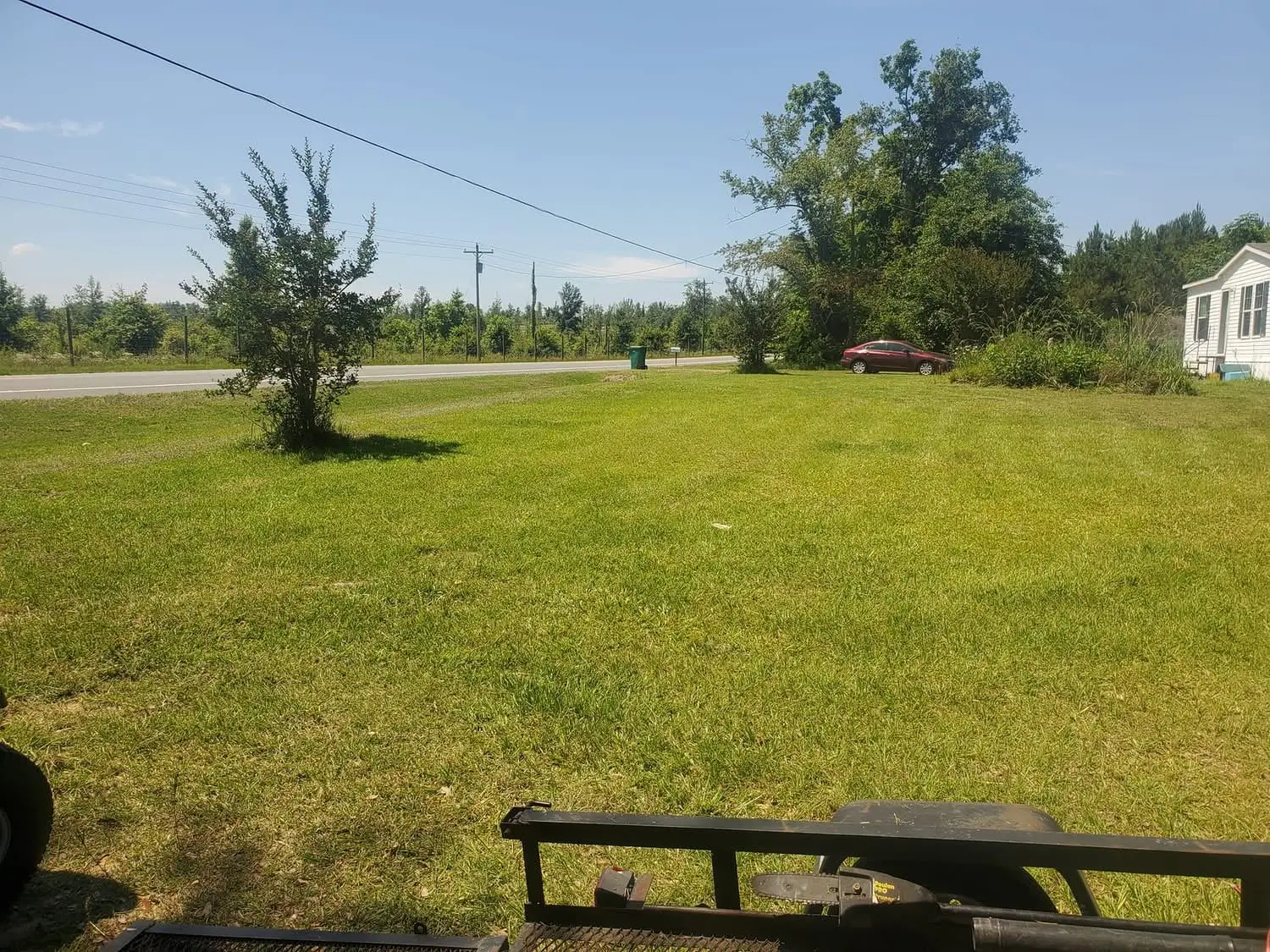 A roadside lot in the Florida Panhandle freshly mowed level from the highway shoulder back toward the home