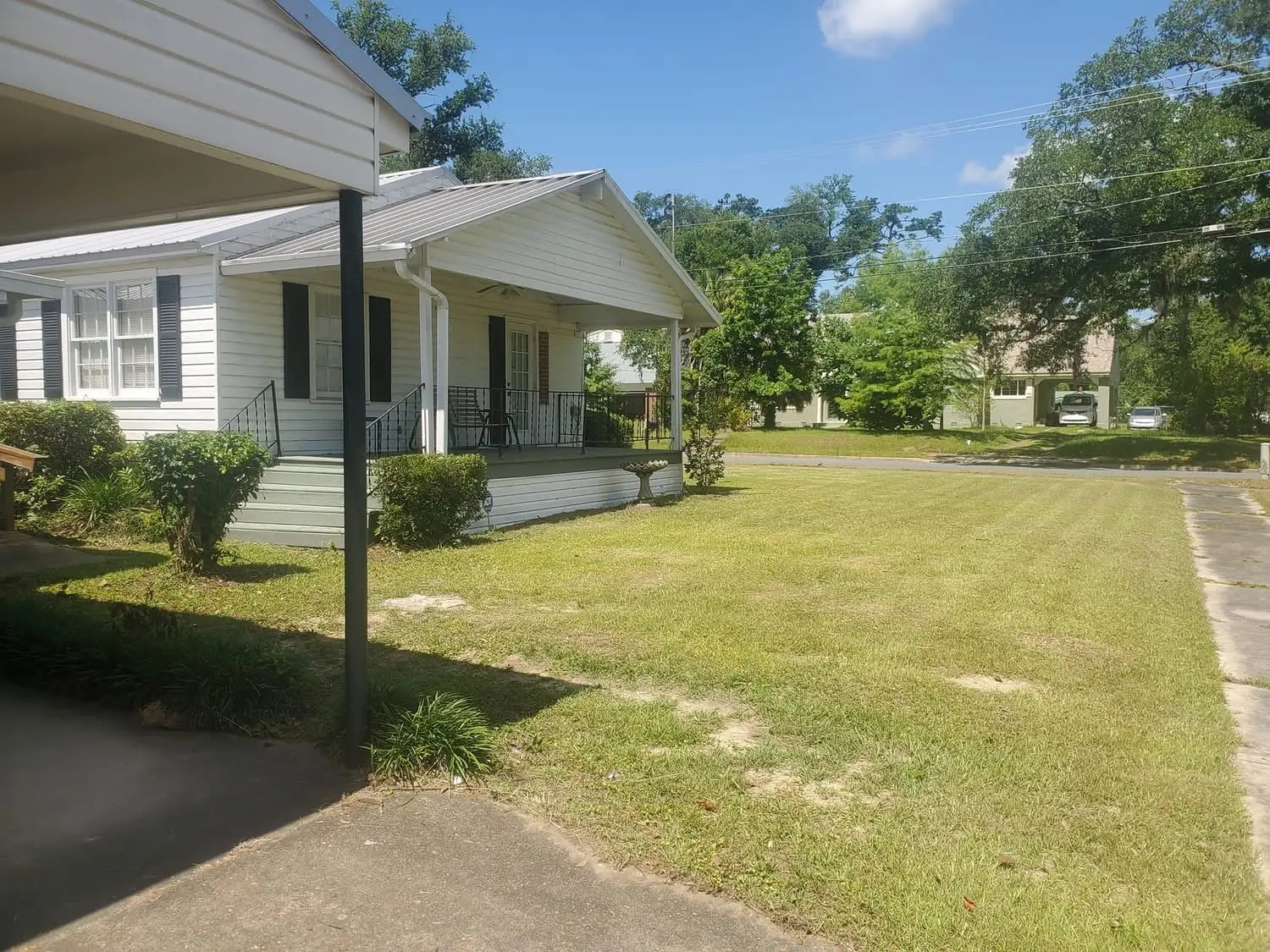 A neighborhood front lawn cut in clean stripes along the sidewalk on a shaded Florida Panhandle street